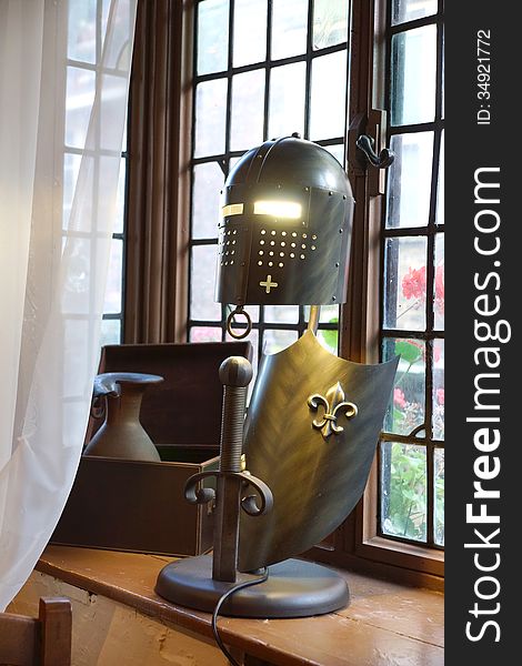 A lamp made from a Knights helmet and shield with a sword sticking out of the base, the eyes illuminated by the inside light. A lamp made from a Knights helmet and shield with a sword sticking out of the base, the eyes illuminated by the inside light