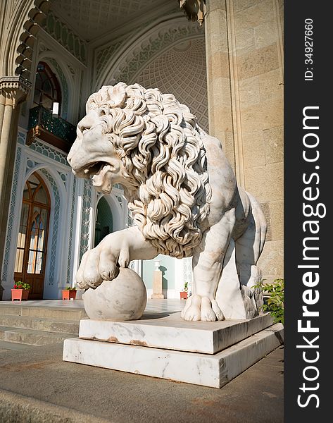Sculpture of lion with a ball on a background of palace