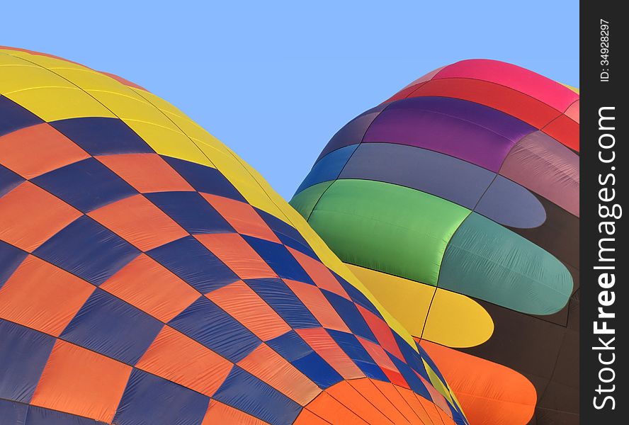 Two colorful hot air balloons being inflated. Blue sky in background. Two colorful hot air balloons being inflated. Blue sky in background.