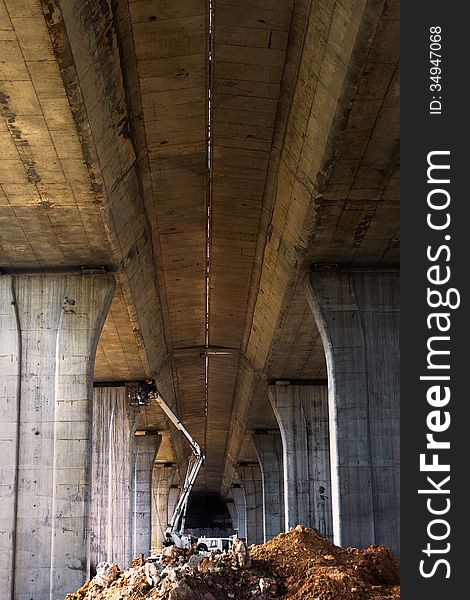 Workers maintaining bridge pier with construction machinery. Workers maintaining bridge pier with construction machinery