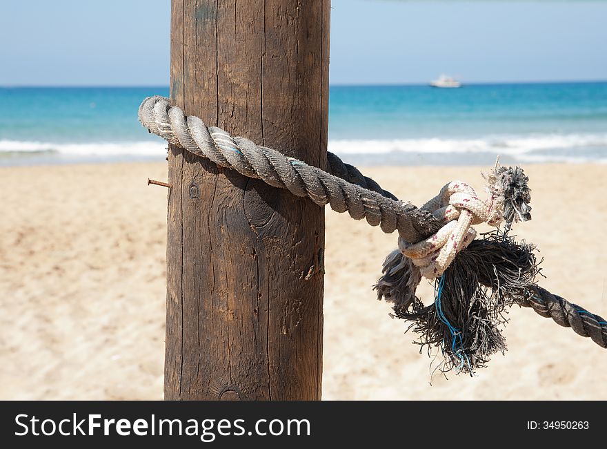 Marine rope tied to a wooden post photographed against a background of sea. Marine rope tied to a wooden post photographed against a background of sea