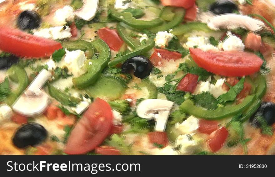 Vegetarian pizza close-up turns, showing all of its stuffing: peppers, olives, tomatoes, mushrooms, feta cheese, mozzarella