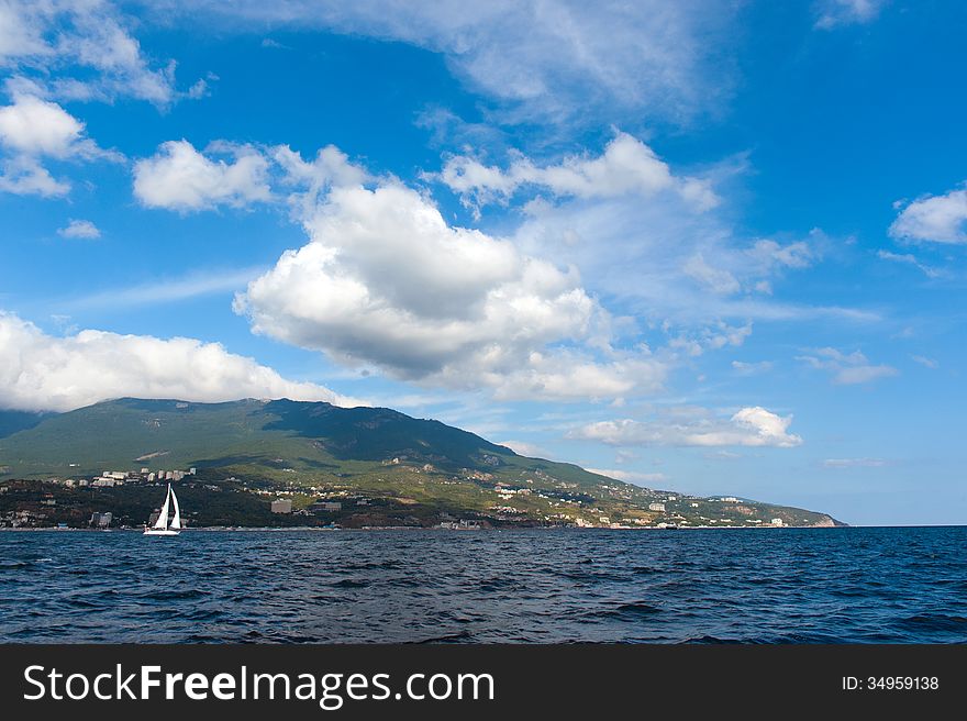 Yacht and blue water ocean. Shore the background. Yacht and blue water ocean. Shore the background