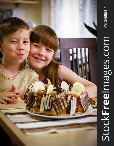 Children sit near a table and eat a cake. Children sit near a table and eat a cake