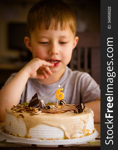 The boy looks at the birthday cake. The boy looks at the birthday cake