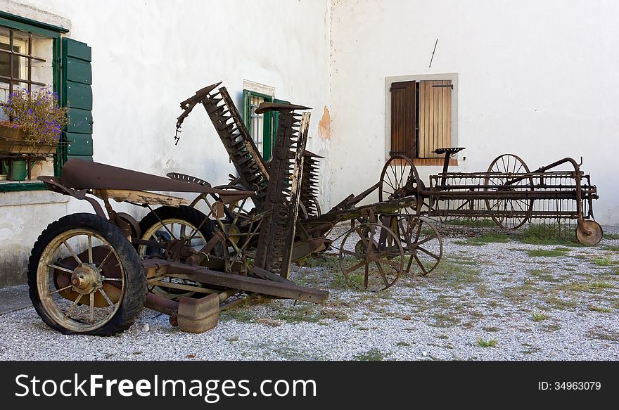 Old Farming tools and vehicles outside a country house