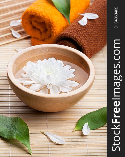 Towels and white daisy in wooden bowl. Spa and body care. Towels and white daisy in wooden bowl. Spa and body care