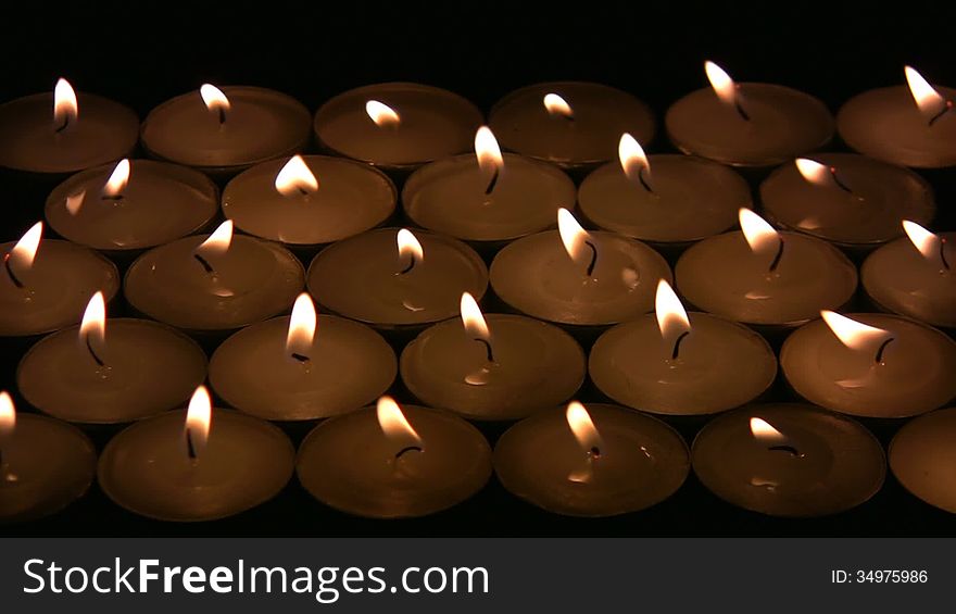 Flame (fire) of many candles vibrate on a wind. A black background
