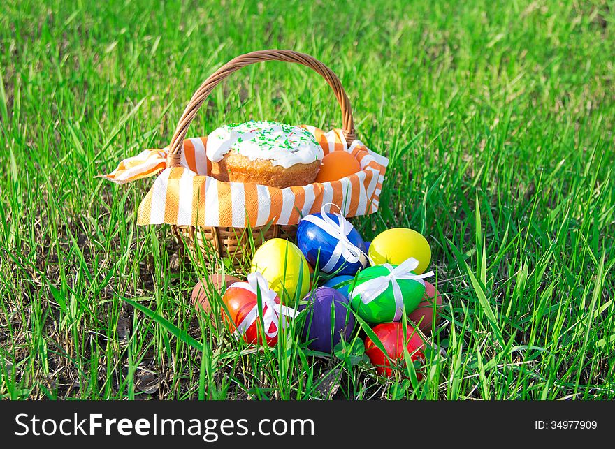 Easter cake on a striped napkin in a basket and eggs on green spring grass. Easter cake on a striped napkin in a basket and eggs on green spring grass