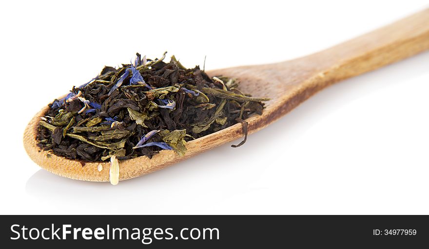 Fragrant dry tea leaves with cornflowers in the wooden spoon, on white