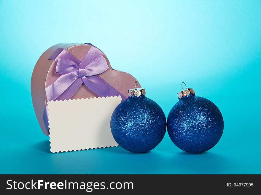Original gift box heart, Christmas spheres and blank card on a blue background