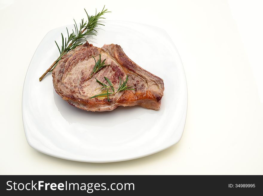 Beefsteak with rosemary on white table.