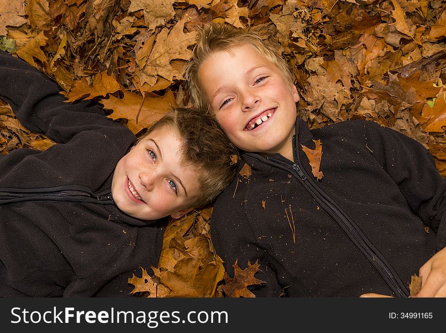 Kwo kids laying in a pile of leaves. Kwo kids laying in a pile of leaves