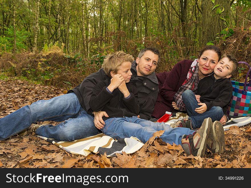 Happy family relaxing in a forest, enjoying fall. Happy family relaxing in a forest, enjoying fall