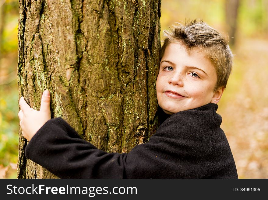 Kid in a forest hugging a tree. Kid in a forest hugging a tree