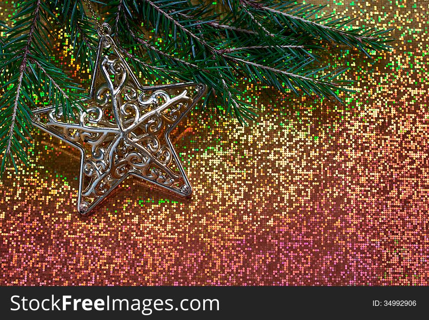 Fir branch decorated with a star on a brilliant background