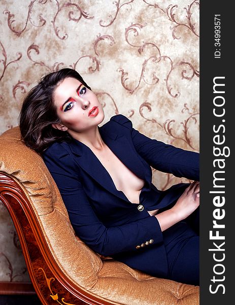 Gorgeous woman in suit on brown couch. Gorgeous woman in suit on brown couch