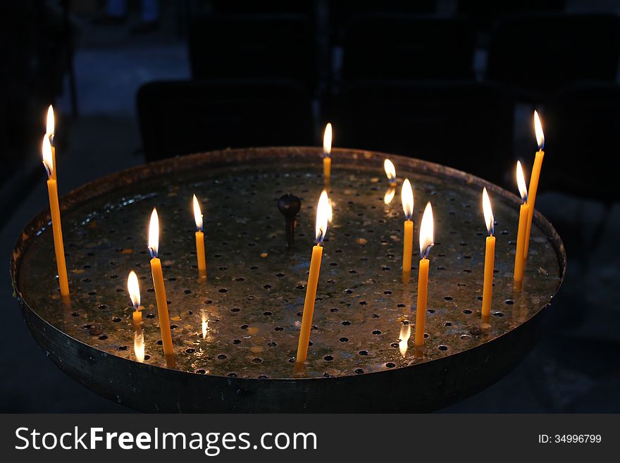 Bright burning church candles on candlesticks in church