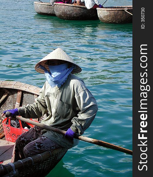 A totaly covered vietnamese woman in a traditional boat. A totaly covered vietnamese woman in a traditional boat