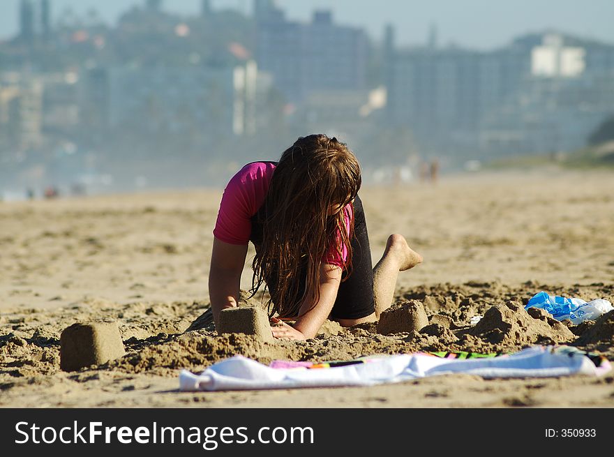 Little girl building sand castles on a beach. Little girl building sand castles on a beach