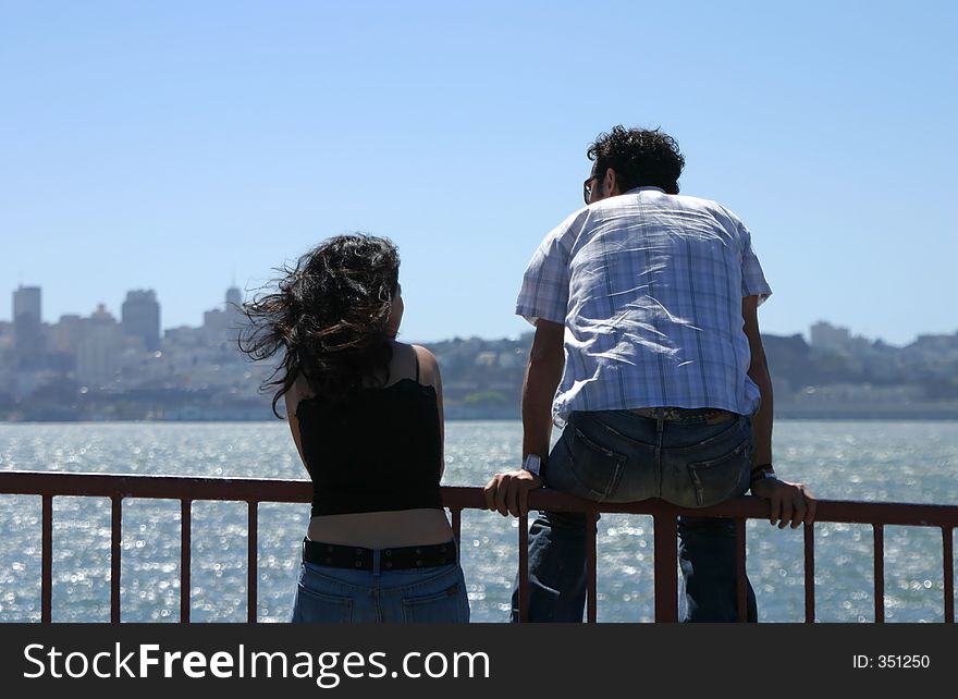 A young couple enjoys a sunny day at the shore of the bay. A young couple enjoys a sunny day at the shore of the bay.