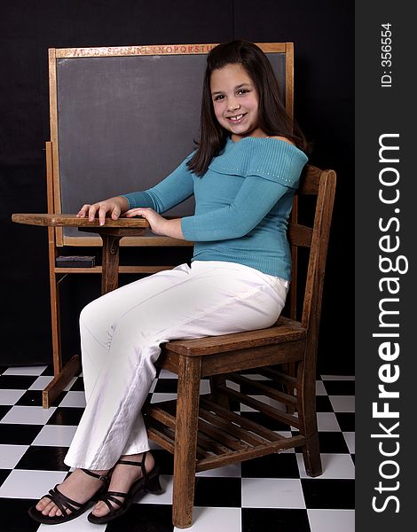Adolescent girl sitting at desk in classroom setting. Adolescent girl sitting at desk in classroom setting