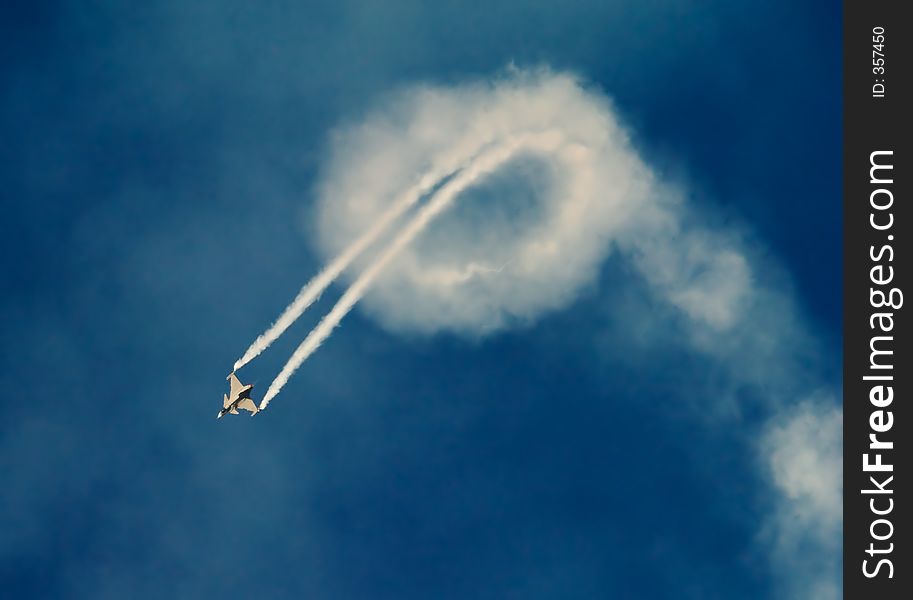 Jetfighter plane flying loops with plume of smoke. Jetfighter plane flying loops with plume of smoke