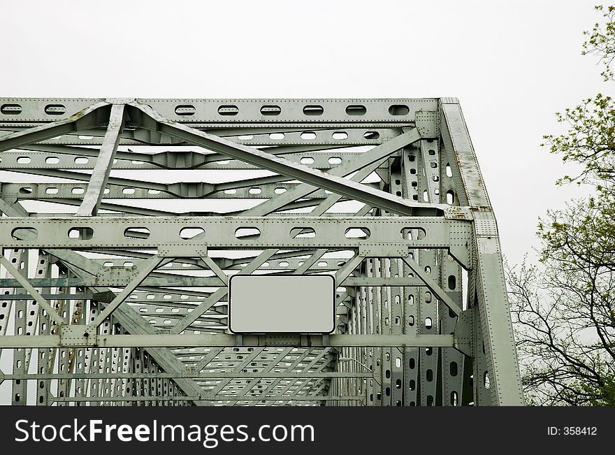 Steel bridge with blank sign. It is a overcast day.