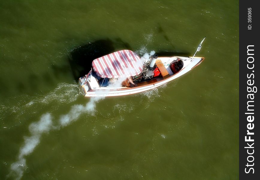 A solo steam boat passes under the camera with a trail following. A solo steam boat passes under the camera with a trail following