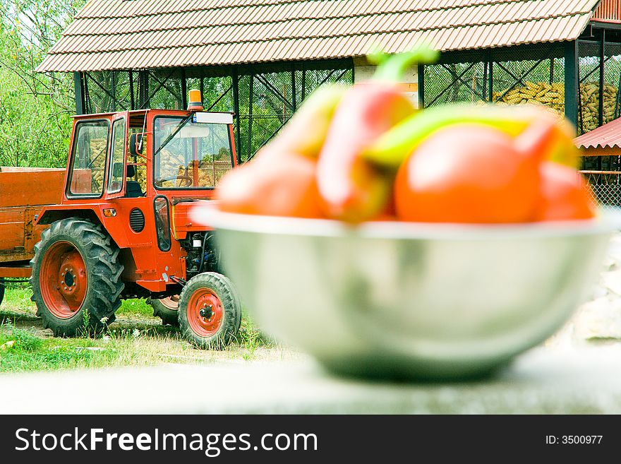 Fresh vegetables in bowl at a farm, with a tractor in background, focus on tractor