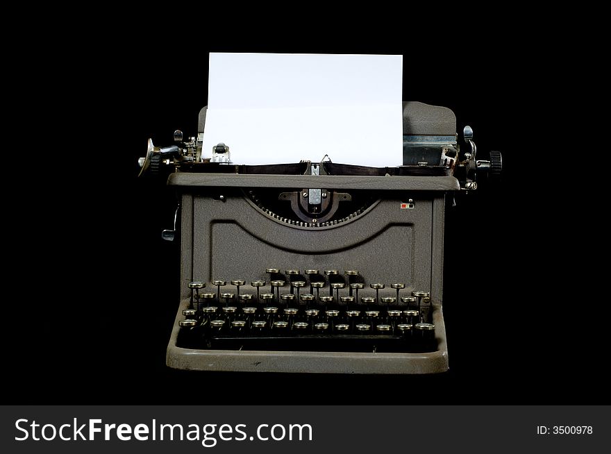 A gray silver vintage typewriter on black background with copy space on the paper in the typewriter carriage