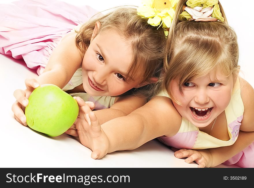 Two beautiful children struggle for apple over white. Two beautiful children struggle for apple over white