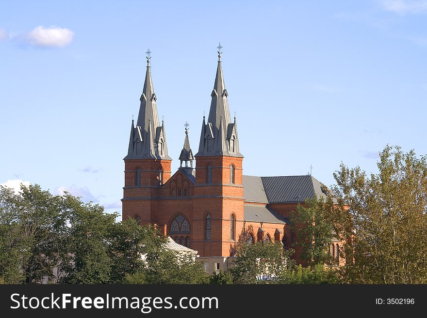 A red church stands against a cloudy blue sky. A red church stands against a cloudy blue sky.