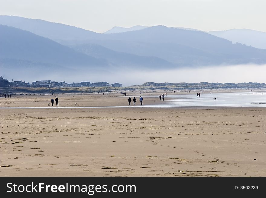 Coast covered with mist,  people walking on the beach, Manzanita OR. Coast covered with mist,  people walking on the beach, Manzanita OR