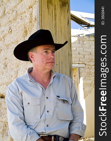 A man leaning against the wall of an abandoned adobe brick structure. A man leaning against the wall of an abandoned adobe brick structure.