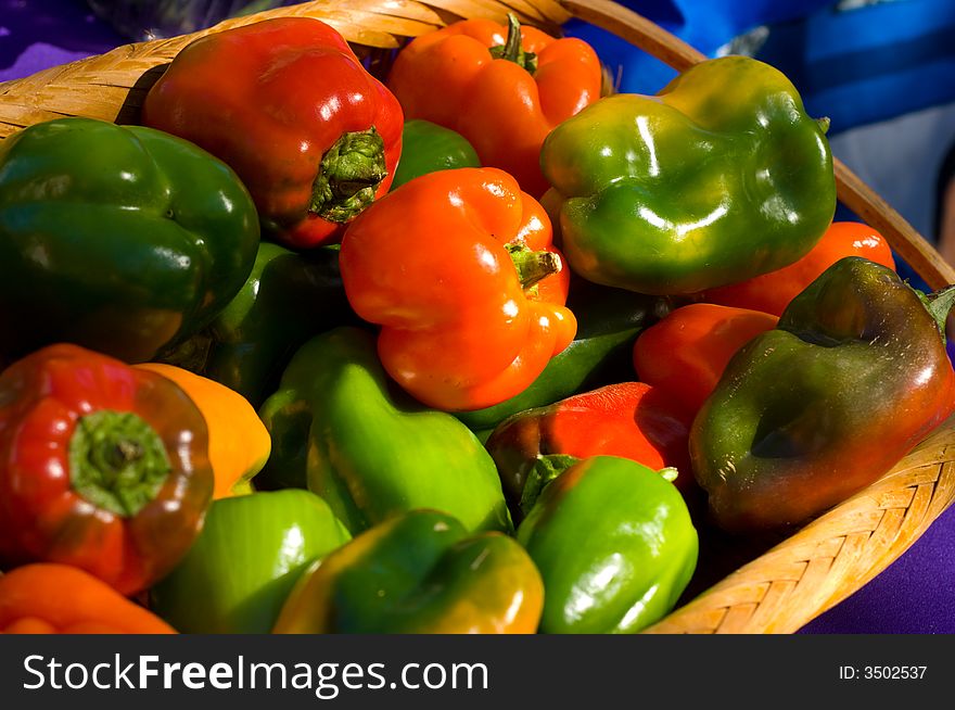 A basket full of fresh, farm grown bell peppers painted with sunlight at a farmer's market. A basket full of fresh, farm grown bell peppers painted with sunlight at a farmer's market