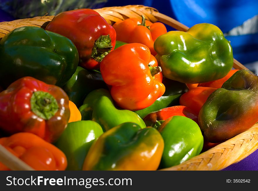 A basket full of fresh, farm grown bell peppers painted with sunlight at a farmer's market. A basket full of fresh, farm grown bell peppers painted with sunlight at a farmer's market