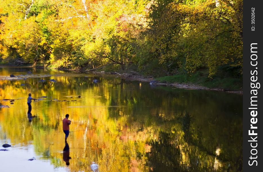 A Fall scene of two fishermen in a shallow river. Trees reflect colors. Looks l ike a watercolor - no filters used. A Fall scene of two fishermen in a shallow river. Trees reflect colors. Looks l ike a watercolor - no filters used.