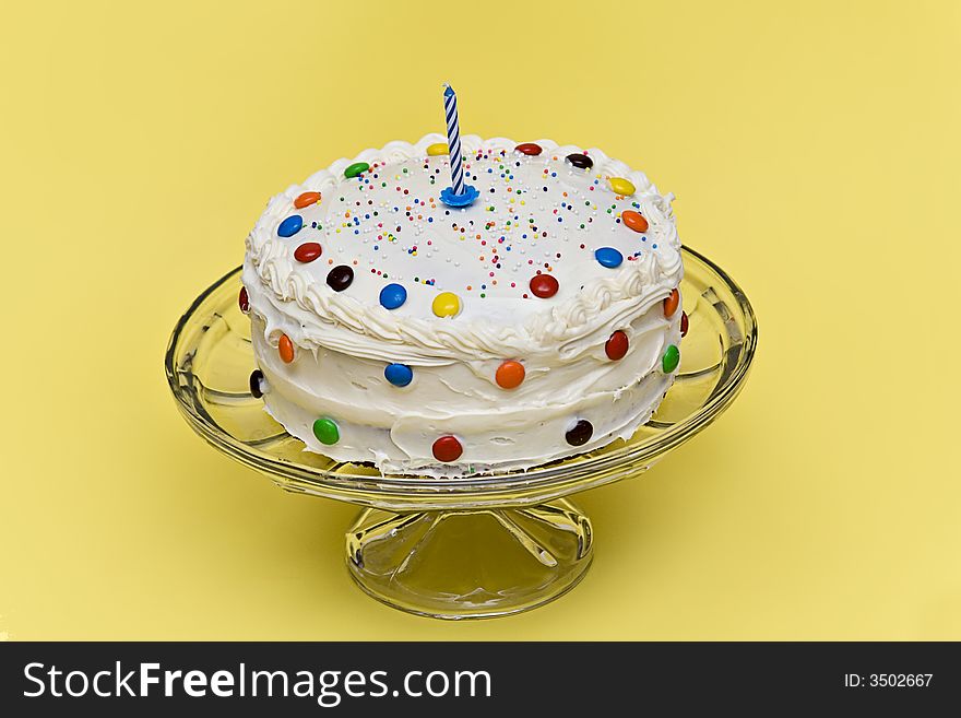 A party cake decorated with candies, sprinkles and a candle. A party cake decorated with candies, sprinkles and a candle.