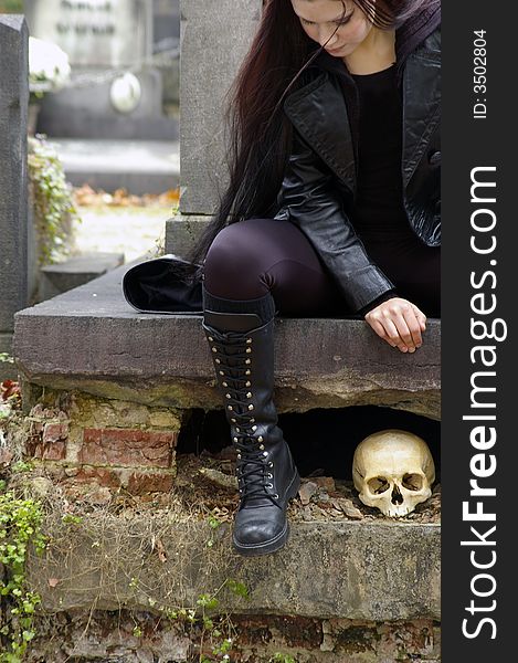 Woman in a european ancient cemetery with human skull. Woman in a european ancient cemetery with human skull.