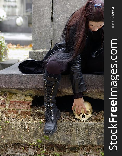 Woman in a european ancient cemetery with human skull. Woman in a european ancient cemetery with human skull.