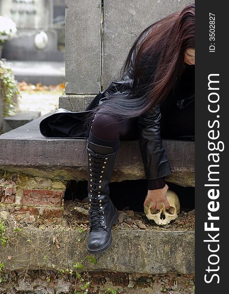 Woman in a european ancient cemetery with human skull. Woman in a european ancient cemetery with human skull.