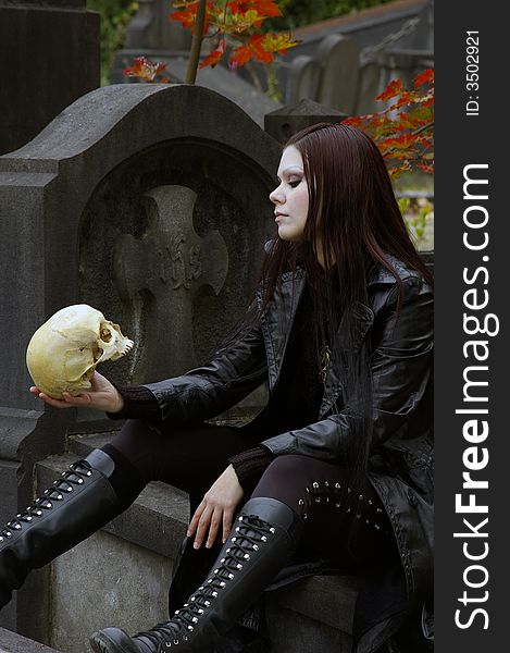 Woman in a european ancient cemetery with human skull. Woman in a european ancient cemetery with human skull.