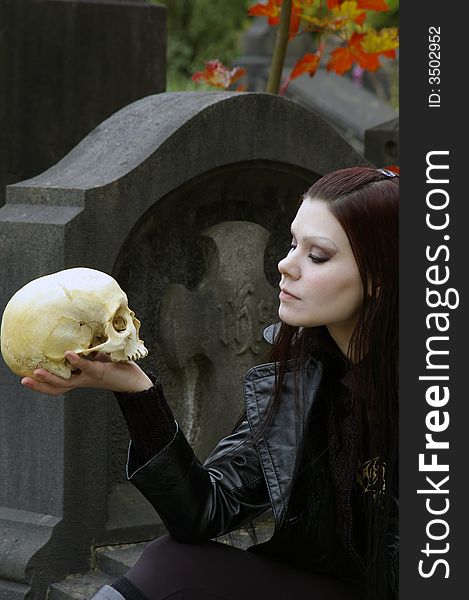 Woman in a european ancient cemetery with human skull. Woman in a european ancient cemetery with human skull.