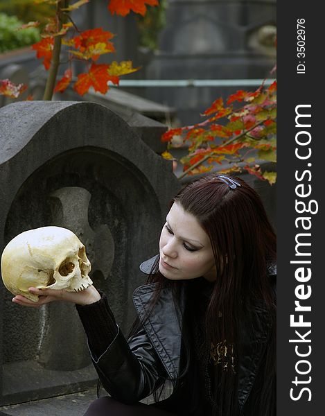 Woman in a european ancient cemetery with human skull. Woman in a european ancient cemetery with human skull.