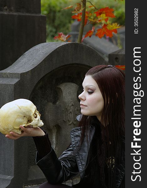 Woman in a european ancient cemetery with human skull. Woman in a european ancient cemetery with human skull.