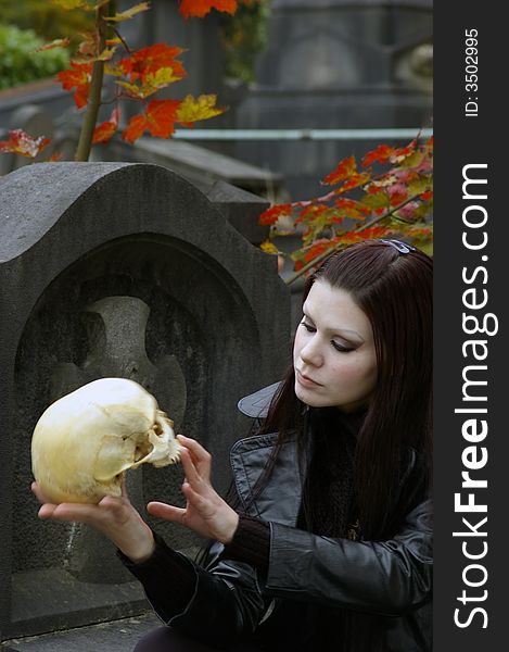 Woman in a european ancient cemetery with human skull. Woman in a european ancient cemetery with human skull.