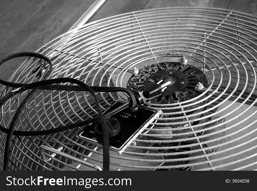 Close-up of a dusty vintage electic fan laying on wooden floor. (mood shot, grainy, background, black and white shot)