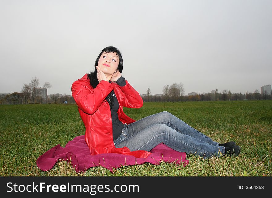 Black head woman is sitting on a Plaid in park grass