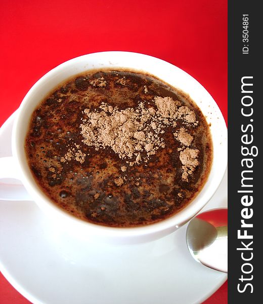 White cup of coffee with spoon on red background